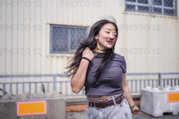 Three quarter length photo of a young cool asian girl dancing k-pop outdoors in an industrial building