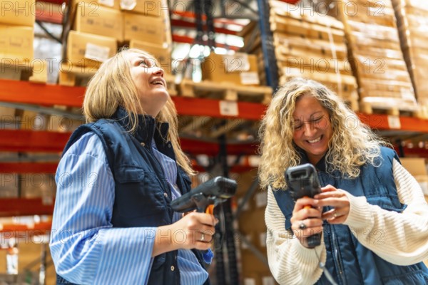 Happy blonde two female workers scanning boxes in a distribution warehouse
