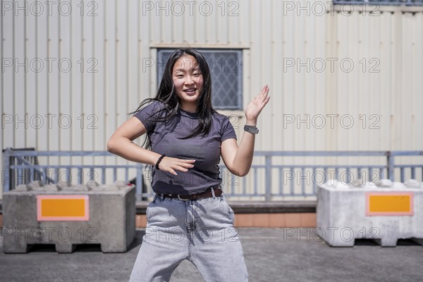 Urban female asian young dancer dancing k-pop in the city in an urban industrial space