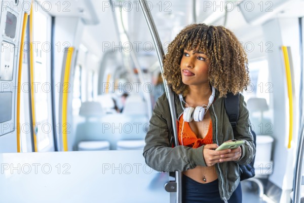 Distracted latin young beauty woman with curly hair looking away while using phone in a metro