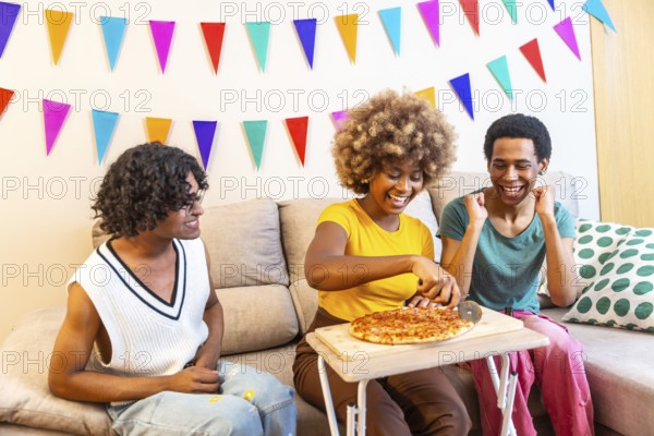 Multi-ethnic friends cutting and sharing pizza at home during party