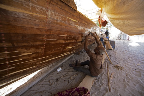 Indian man working at a dhow shipyard in Sur, Janub ash-Sharqiyya province, Oman, Asia