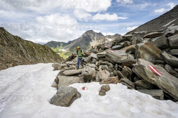 Mountaineer on a hiking trail in boulder terrain with snow, Lasörling Höhenweg, Lasörling Group, Hohe Tauern National Park, East Tyrol, Tyrol, Austria, Europe