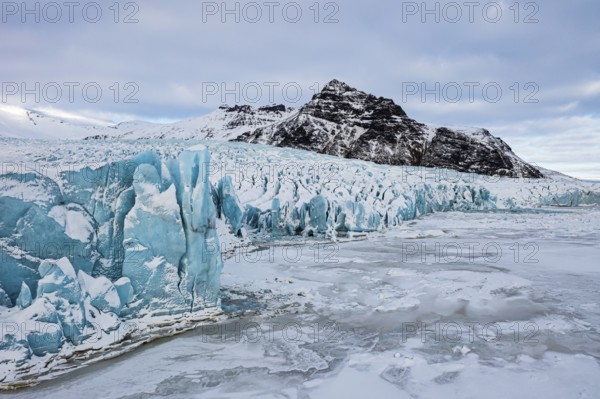 Glacier break-off and snow-covered icebergs in the Fjallsarlon glacier lagoon, with the Öraefajökull glacier in the background, drone shot, Sudurland, Iceland, Europe