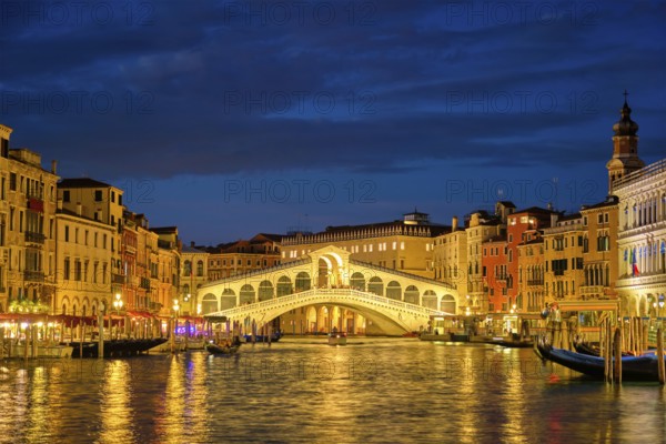 Famous Venetian tourist landmark Rialto bridge (Ponte di Rialto) over Grand Canal illuminated at night in Venice, Italy, Europe
