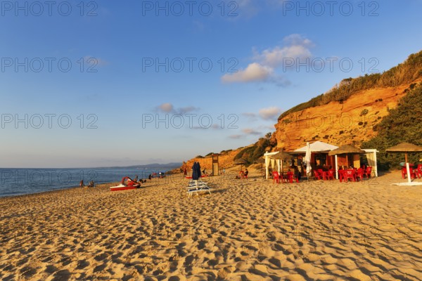 Beach café, red rocks illuminated by the evening sun, sandy beach with tourists, holiday by the sea, Spiaggia di Scivu, Arbus, Costa Verde, Sud Sardegna, Sardinia, Italy, Europe