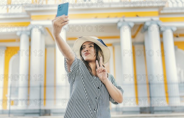 Beautiful tourist girl taking selfie in the cathedral of Granada. Young tourist woman with hat taking selfie in a square. Selfies and vacation concept