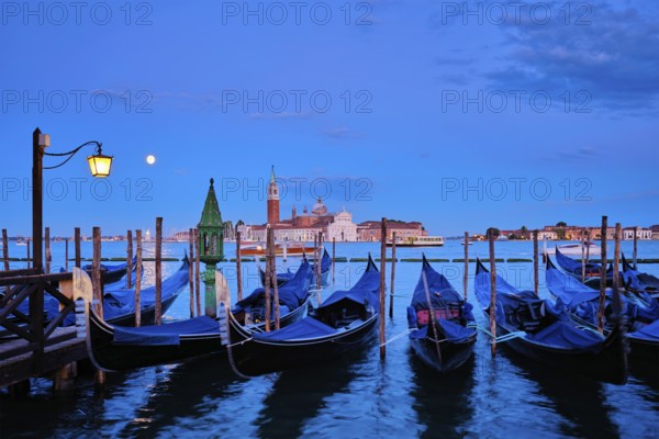 Romantic vacation Venice travel background, gondolas at Saint Mark (San Marco) square and Basilica San Giorgio Maggiore Church seen across Venice lagoon with full moon. Venice, Italy, Europe