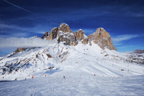 View of a ski resort piste with people skiing in Dolomites in Italy