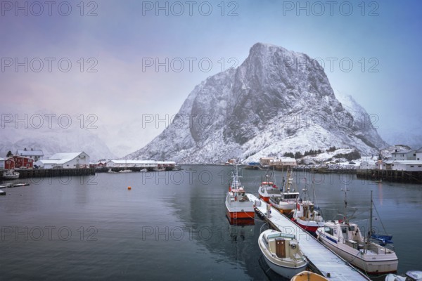 Pier with ships in Hamnoy fishing village on Lofoten Islands, Norway with red rorbu houses. With falling snow