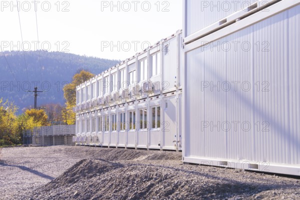 Row of white containers along a gravel path, illuminated by sunlight, refugee accommodation Beermiß, Calmbach, Black Forest, Germany, Europe