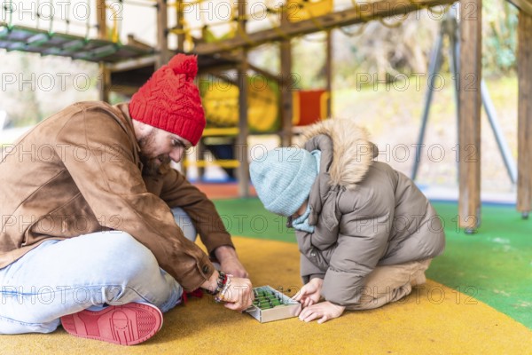 Father and son enjoying a playful moment together, engaging in a table football game at a playground