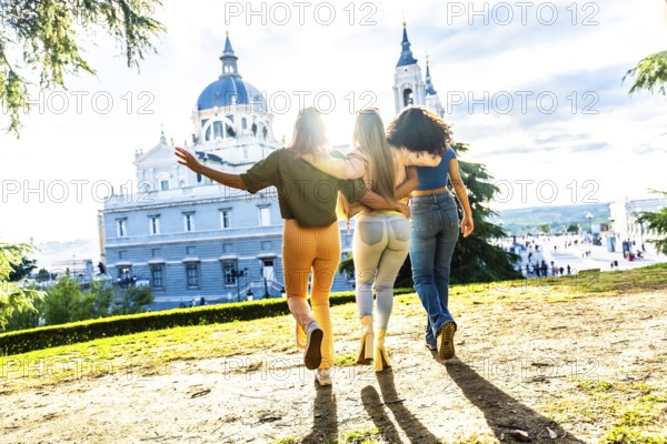 Rear view of three women embraced for the back contemplating city views during sunset