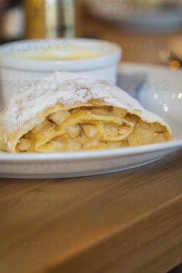 Close-up of an apple strudel with icing sugar and visible apple pieces on a plate, autumn creations at Cafe Kuh, Deckenpfronn, Germany, Europe