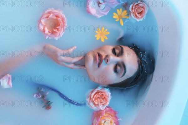 Artistic portrait from above of a beautiful caucasian woman in flowered milk bath