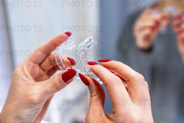 Close-up of a hands of a caucasian woman holding an invisible aligner in the toilet