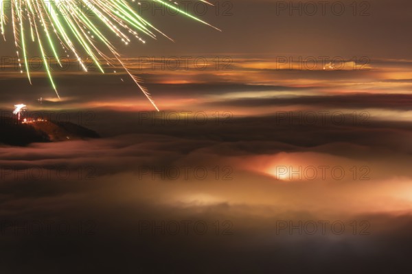 New Year's Eve fireworks 2024 and a little red Aurora Borealis Northern Lights. On the Breitenstein, Swabian Alb near Ochsenwang. Sea of fog in the foothills of the Alb. View towards Stuttgart. In the foreground, the Hörnle near Teck looks out of the fog