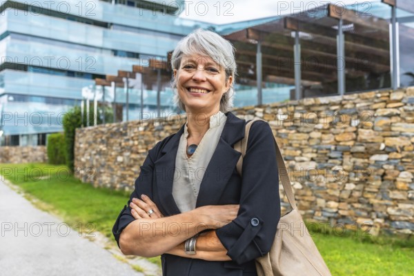 Portrait of a smiling mature businesswoman standing proud with arms crossed outdoors in a financial district