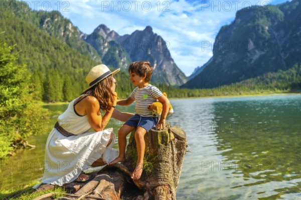 Mother and son sharing a tender moment while enjoying the breathtaking view of lake dobbiaco and the dolomites during their summer vacation