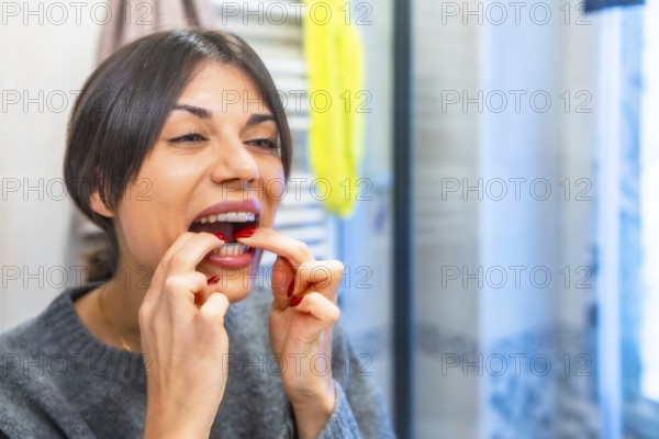 Beauty caucasian woman putting on her clear retainer in the bathroom mirror