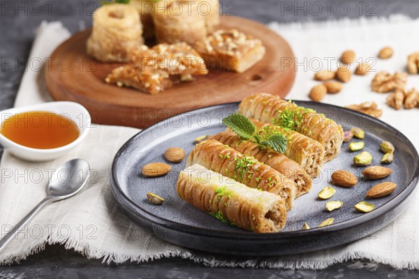 Set of various traditional arabic sweets: baklava, kunafa, basbus in ceramic plates on a gray concrete background. side view, selective focus