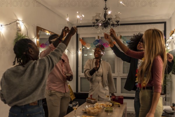 Multi-ethnic happy friends raising burning sparkler celebrating party at night at home