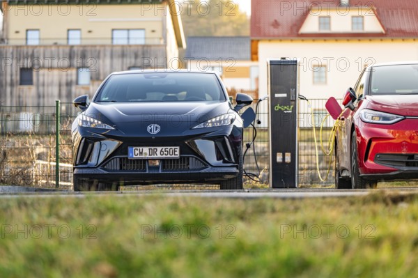 A black electric car being charged next to a charging station in a rural area, Deer E- Carsharing vehicle MG4, Calw district, Germany, Europe