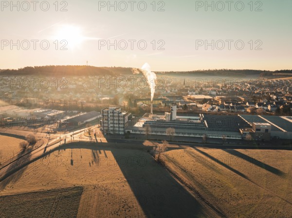 Urban landscape with factory and smoke, surrounded by fields at sunset with long shadows, Althengstett, district of Calw, Germany, Europe