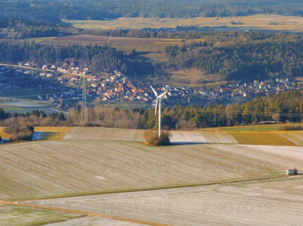 A wind turbine stands in a frosty landscape with a village in the background, district of Calw, Germany, Europe