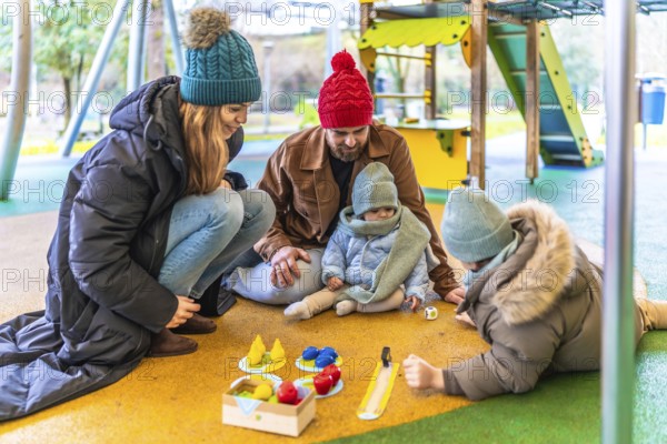 Happy family enjoying quality time together, playing board game at an outdoor playground during winter season