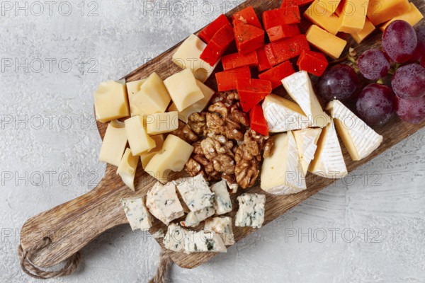 Assorted cheese on a wooden board, with grapes and walnuts, appetizer, no people