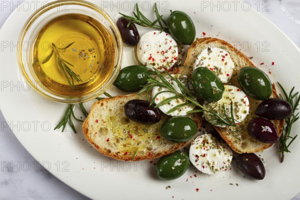A plate with a snack, ciabatta bread with cheese and olives, olive oil, spices and herbs, top view, no people