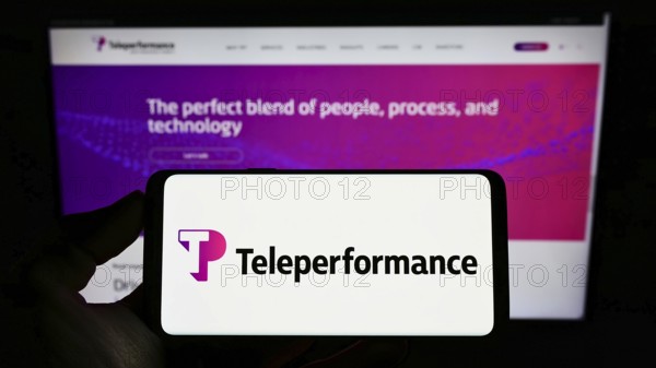 Stuttgart, Germany, 05-21-2022: Person holding cellphone with logo of French outsourcing company Teleperformance SE on screen in front of webpage. Focus on phone display, Europe