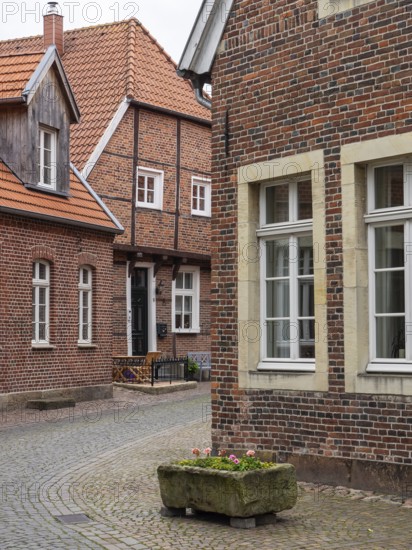 Paved village street with old brick buildings and blooming flower box, Legden, münsterland, westphalia, germany