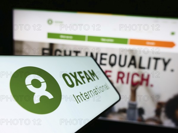 Stuttgart, Germany, 01-21-2023: Cellphone with logo of confederation Oxfam International on screen in front of website. Focus on center-left of phone display, Europe