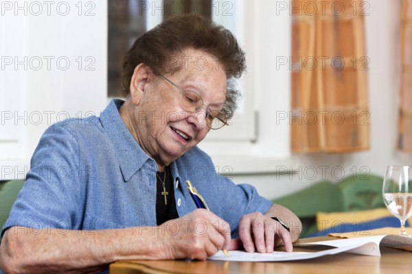 An old woman signs a letter, 75, 80, years, senior studio shot, Federal Republic of Germany