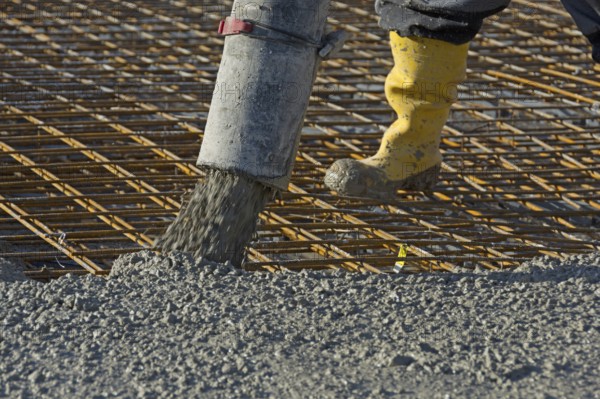 Construction worker pours concrete onto reinforcing steel using a concrete pump