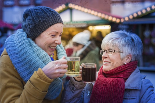 Two woman standing at the Christmas market drinking mulled wine