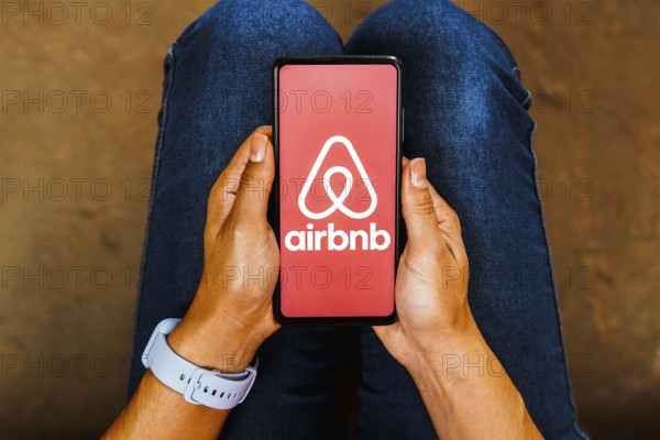 In this photo illustration, the Airbnb logo is displayed on a smartphone screen