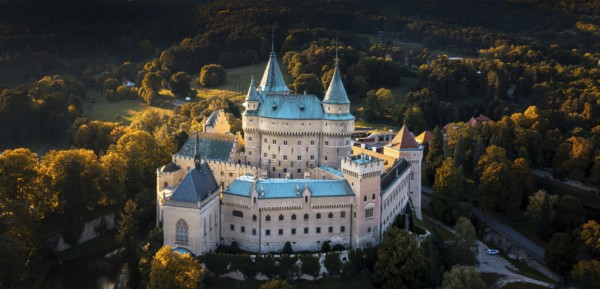 Bojnice, Slovakia, 26 September, 2022: aerial panorama view of Bojnice Castle in Slovakia surrounded by forest in warm evening light, Europe