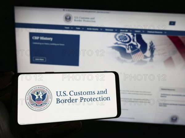 Stuttgart, Germany, 10-29-2023: Person holding smartphone with seal of agency United States Customs and Border Protection (CBP) in front of website. Focus on phone display, Europe
