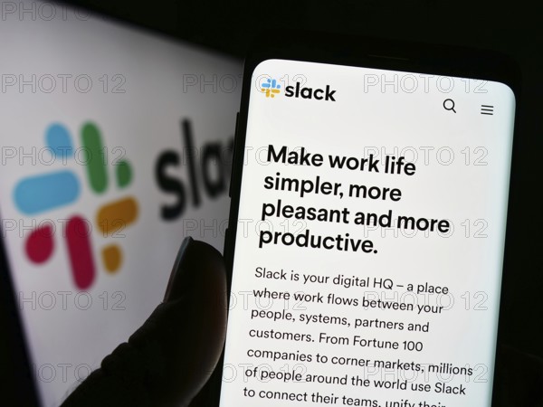 Stuttgart, Germany, 12-30-2022: Person holding cellphone with webpage of US software company Slack Technologies LLC on screen in front of logo. Focus on center of phone display, Europe