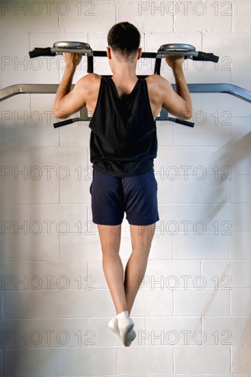A young man performs exercises to strengthen his back in a gym, supervised by an instructor. This training seeks to improve his muscles and posture for optimal physical well-being