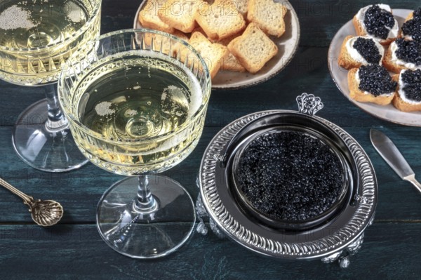 Caviar and champagne, vintage style, with bread and toasts on a dark blue wooden background