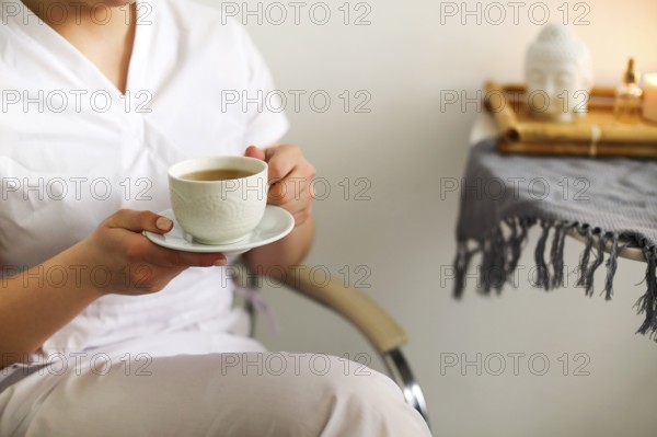 Cropped photo of happy lovely young female health worker laughing sincerely while holding cup of hot tea, enjoying coffee break and spending time with coworkers in medical clinic. Vertical shot
