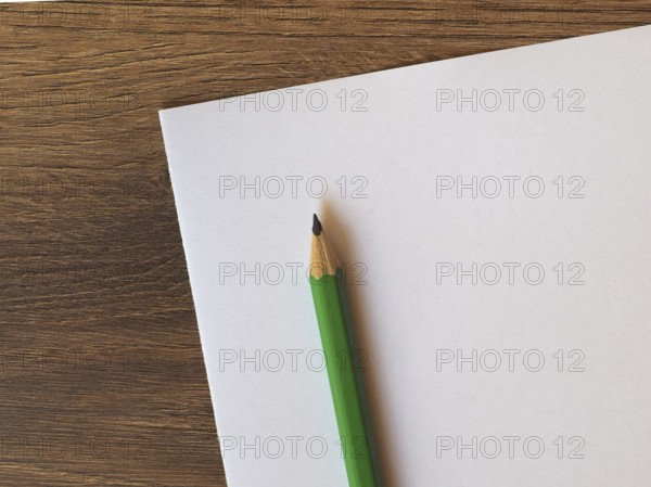 Green pencil on paper sheet desk