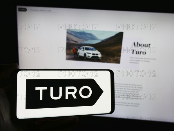 Stuttgart, Germany, 03-18-2024: Person holding smartphone with logo of US peer-to-peer carsharing company Turo Inc. in front of website. Focus on phone display, Europe