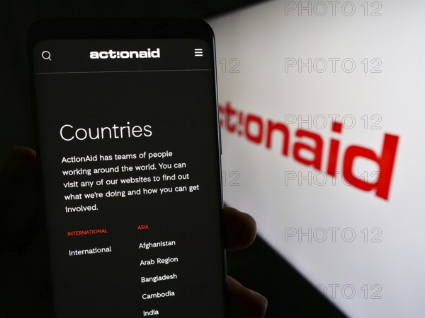 Stuttgart, Germany, 10-08-2023: Person holding smartphone with webpage of international charity organization ActionAid in front of logo. Focus on center of phone display, Europe