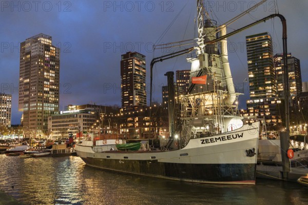 Illuminated ship in the harbour with skyscrapers in the background at night, Rotterdam, Netherlands