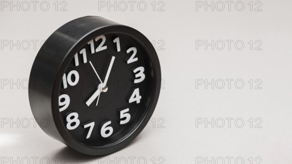 Circular black alarm clock against gray background